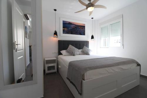a white bedroom with a bed and a ceiling fan at Apartamento Ama Altea in Altea