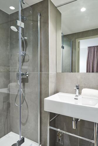 une salle de bain avec un lavabo et une douche dans l'établissement Hotel Cervantes by Happyculture, à Paris