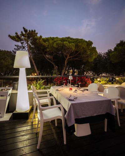 a table with white chairs and a lamp on a deck at Raffaello Hotel & Mooka Restaurant in Senigallia