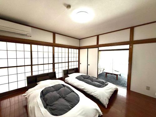 two beds in a room with large windows at 楓リゾート鬼怒川温泉 优雅宽敞的日式独栋旅馆 in Nikko