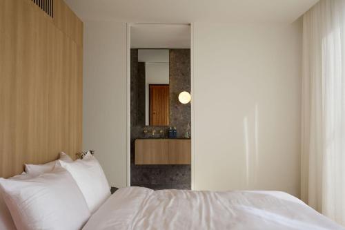 a bedroom with a white bed and a mirror at Zoarii Luxury Beach Front Wellness Stay in Ventnor
