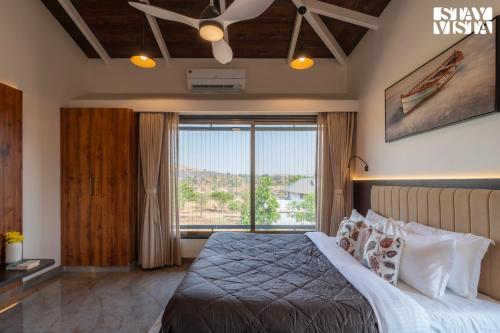Un dormitorio con una cama y una ventana grande. en StayVista at Daisy Dell with Pool, Gazebo, Wi-Fi, en Nashik