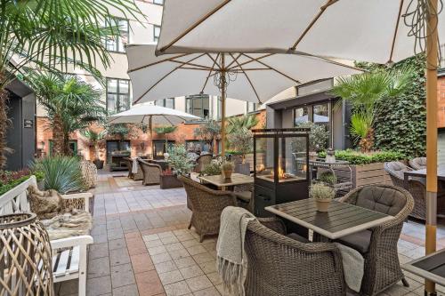 an outdoor patio with tables and chairs and umbrellas at Best Western Hotel Hebron in Copenhagen