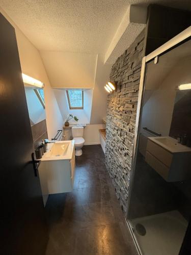 La salle de bains est pourvue de toilettes et d'un mur en pierre. dans l'établissement Chaleureux T2 avec bureau, à Sigoyer