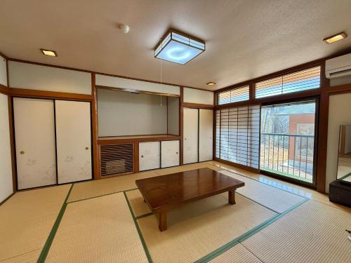a living room with a table and some windows at 楓リゾート鬼怒川温泉 优雅宽敞的日式独栋旅馆 in Nikko