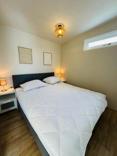 a large white bed in a bedroom with a window at Willem's Beachhouse in Noordwijk