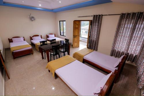 a room with four beds and a table and chairs at sky blue villa in Vythiri