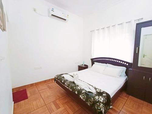a bedroom with a white bed with a wooden floor at Boganvilla, Magic Land Resort in Athirappilly