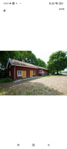 a red building with a tree next to a field at Drängstugan in Kolbäck