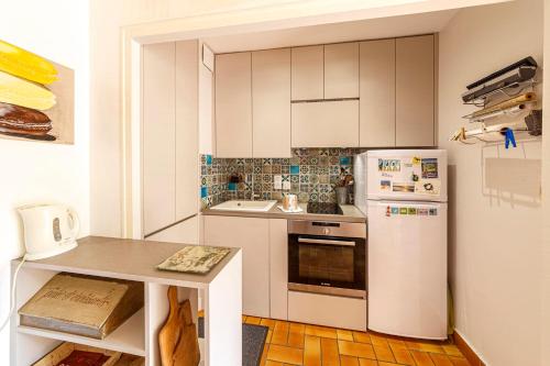 une cuisine avec des armoires blanches et un réfrigérateur blanc dans l'établissement Le Dinarzh - 500m plage - Terrasse, à Dinard