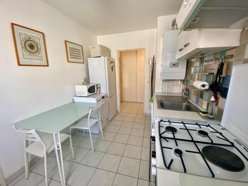 une cuisine avec une table et une cuisinière four supérieur dans l'établissement Spacieux T2 au Rives du Lez, Parking, proche Gares et Centre ville, à Montpellier