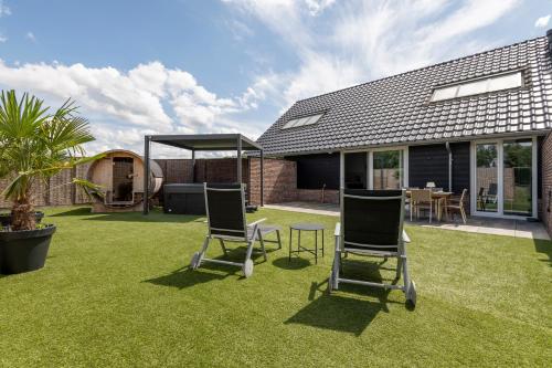 a garden with two chairs and a table on grass at Erve Mulder vakantiehuis met eigen jacuzzi en eigen sauna in Weerselo