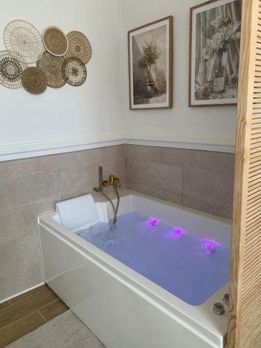 La salle de bains est pourvue d'une baignoire avec des lumières roses. dans l'établissement La Suite Bohème, à Poitiers