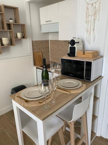 une cuisine avec une table, des verres à vin et un four micro-ondes dans l'établissement La Suite Bohème, à Poitiers