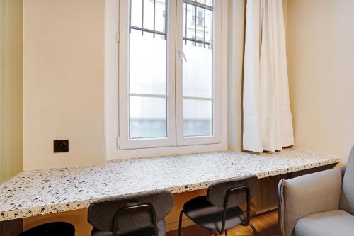 - une fenêtre dans une pièce avec un comptoir et des chaises dans l'établissement 4-star apartment just 12 mn from Sacré-Cœur, à Paris