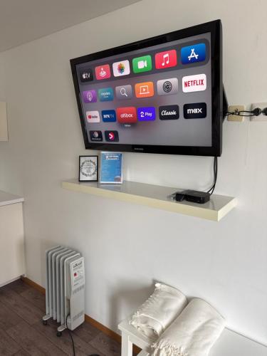 a flat screen tv on a wall with a radiator at Sjøberg Hotell og Ferie Leiligheter in Østhusvik