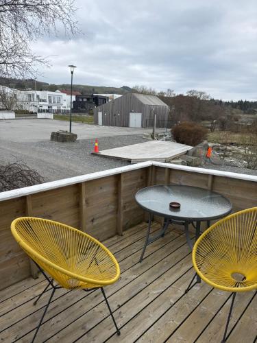 two yellow chairs and a table on a deck at Sjøberg Hotell og Ferie Leiligheter in Østhusvik