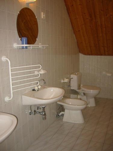 a bathroom with three toilets and a sink and a mirror at Gründner Vendégház in Siófok