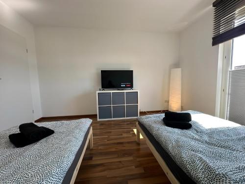 two beds in a room with a tv on the wall at FeWo Lindenallee III Modernes Apartment in Nordhorn