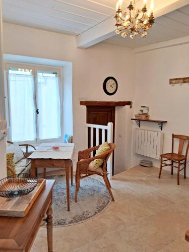 a living room with a table and chairs and a clock at La Petite Romance - Gîte 3 étoiles in Siran