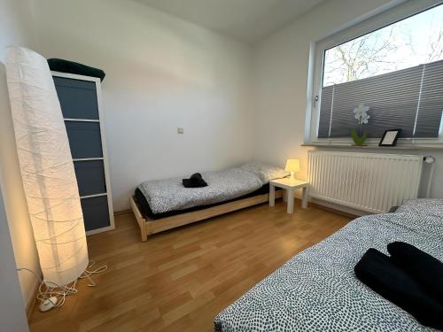 a bedroom with two beds and a large window at FeWo Lindenallee III Modernes Apartment in Nordhorn