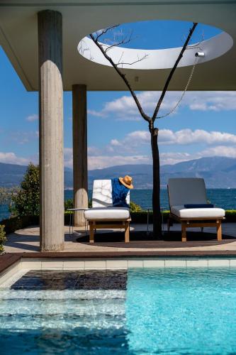 a person sitting in a chair next to a swimming pool at Lefkon Villa with pool by the Sea - NPeloponnese in Kato Rodini