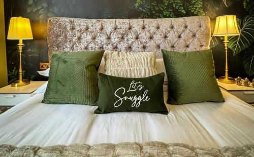 a bed with green and white pillows and two lamps at Brean Views in Weston-super-Mare