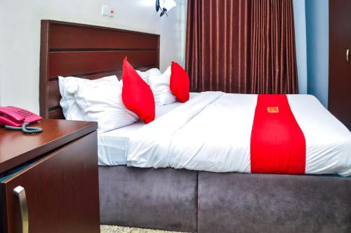 エヌグにあるNafelis Hotel Enuguのベッドルーム1室(赤い枕のベッド1台、電話付)