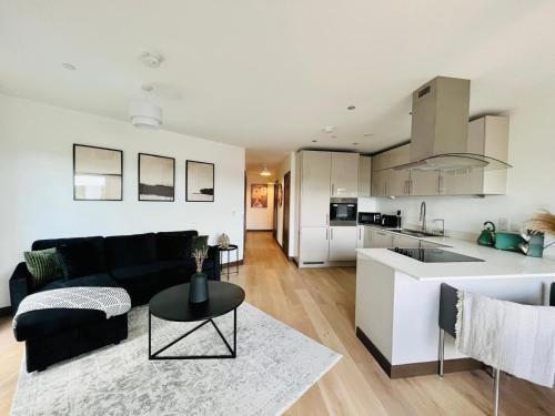 a living room and kitchen with a couch and a table at Spacious Maidstone 2Bed 2Bath - Parking & Balcony - Perfect for Family & Contractors in Maidstone