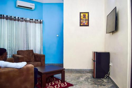 a living room with a couch and a tv at Nafelis Hotel Enugu in Enugu