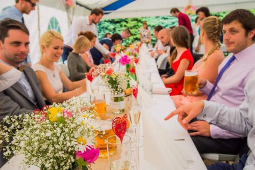a group of people sitting at a long table with flowers at Pension Tereza & Šumavské Roubenky in Sušice