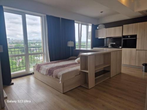 a bedroom with a bed and a kitchen with windows at Skyline Chic Apartment 43 in Chişinău