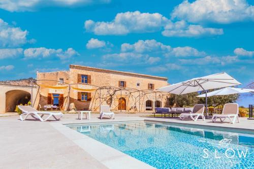 a pool with chairs and umbrellas in front of a building at Villa Son Pons by Slow Villas in Llucmajor