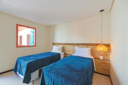 a room with two beds with blue sheets and a window at Casa Manoa Pousada in Maragogi