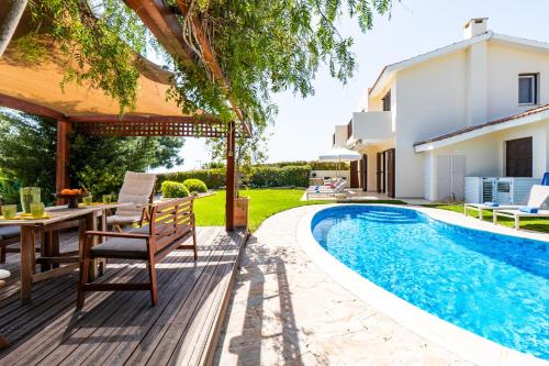 eine Terrasse mit Tisch und Stühlen neben einem Swimmingpool in der Unterkunft Villa Demiana by Ezoria Villas in Coral Bay