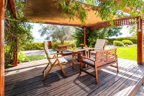 eine Holzterrasse mit einem Tisch und Stühlen darauf in der Unterkunft Villa Demiana by Ezoria Villas in Coral Bay
