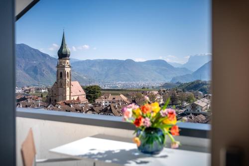 a vase of flowers sitting on a table with a view at Villa Maria Boutique Apartment St Pauls in Appiano sulla Strada del Vino