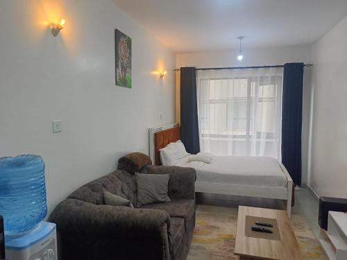 una sala de estar con una cama y un sofá en Legatus Cozy Studios 1, en Nairobi