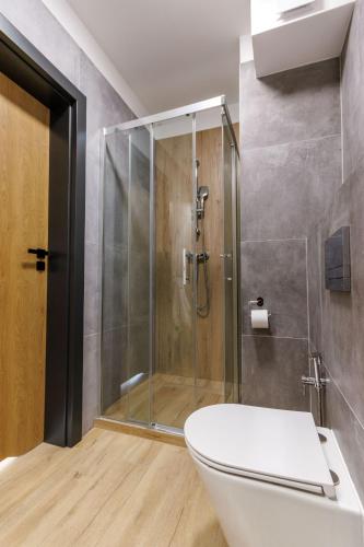 a bathroom with a toilet and a glass shower at Zeus Apartments Lublin in Lublin