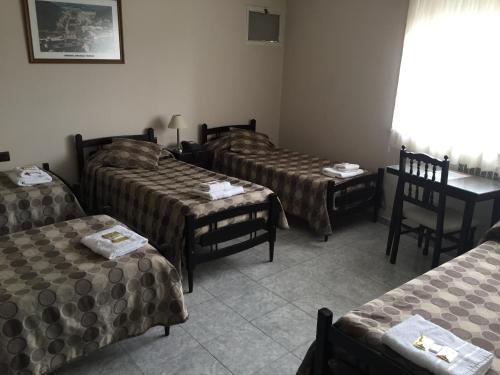 a room with four beds and a table and chairs at Hotel Euzko Alkartasuna in Macachín