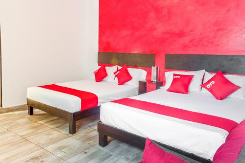 two beds in a room with red and white pillows at OYO Hotel Gandag in Orizaba