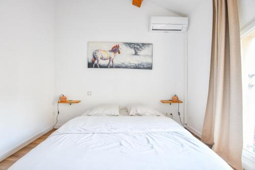 - un lit blanc dans une chambre avec une photo sur le mur dans l'établissement Le Mages - Appart 2 ch avec terrasse et parking, à Marseille