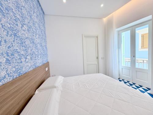 a white bedroom with a blue and white wall at Marina Palace Apartments & Terrace in Lipari