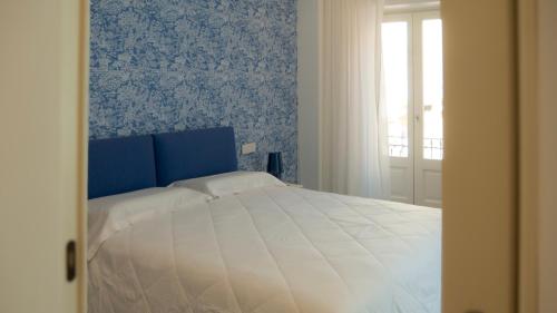 a bedroom with a white bed with blue wallpaper at Marina Palace Apartments & Terrace in Lipari