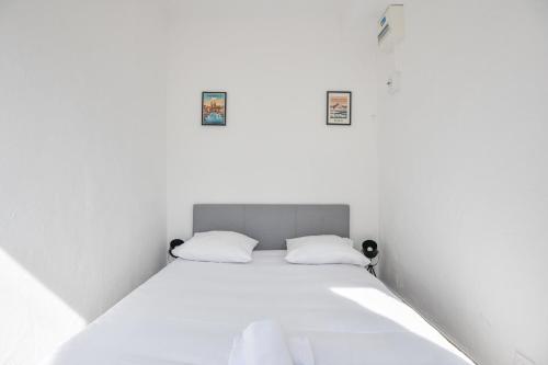 - un lit dans une chambre blanche avec 2 oreillers dans l'établissement Le Saens - Appart 1 ch proche Vieux-Port, à Marseille