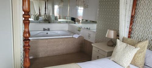 a bathroom with a tub and a bed and a mirror at Royal Court Hotel in Portrush