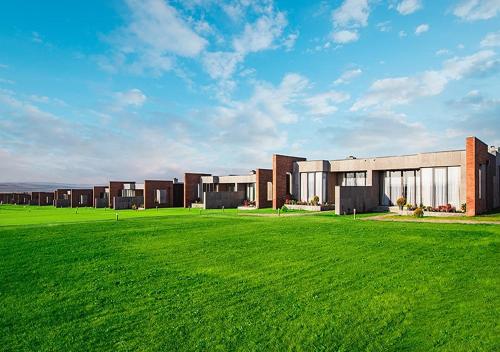 a large building with a green field in front of it at VILLA Kachreti Ambassadori Golf Resort in Kachretʼi