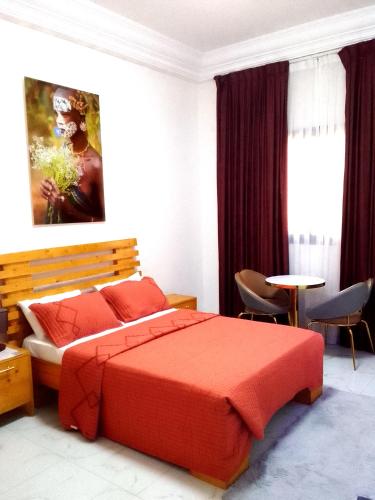a bedroom with a red bed and a table and chairs at La Rouah Mishkan in Dakar