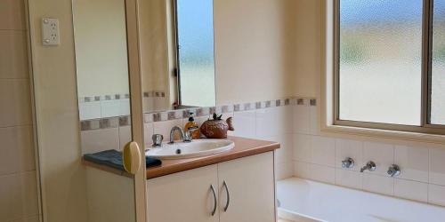 a bathroom with a sink and a window and a tub at The Palms in Loxton