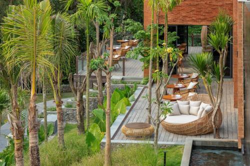 a patio with chairs and tables and palm trees at Garrya Bianti Yogyakarta in Yogyakarta